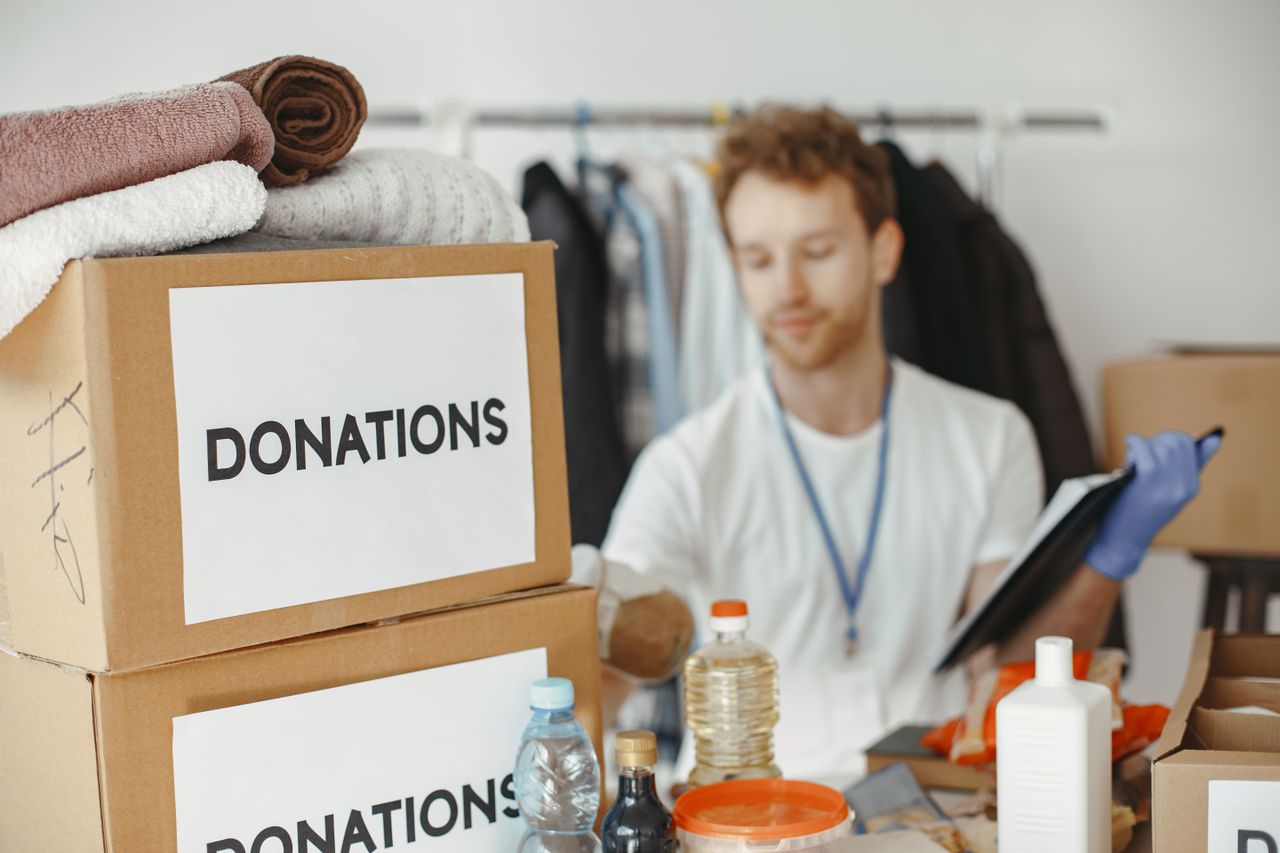about-us Volunteer organizing donation boxes with clothes and supplies for charity.